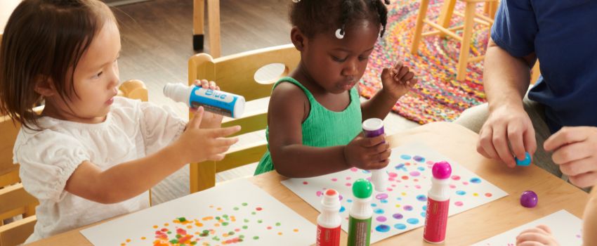 Toddler children using daubers to make dots on paper